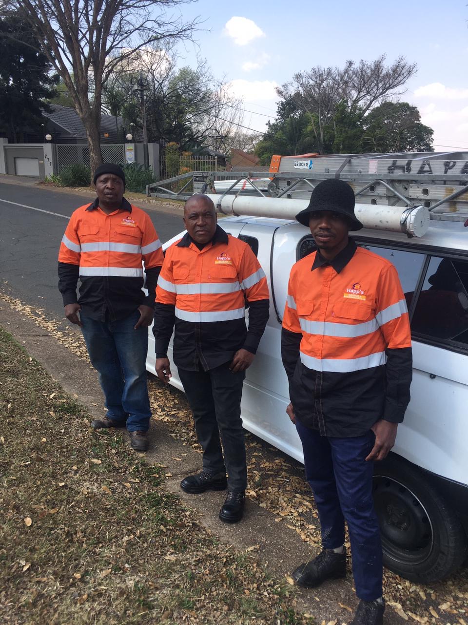 Three Happ's Electrical electricians in branded orange and navy workwear beside their van