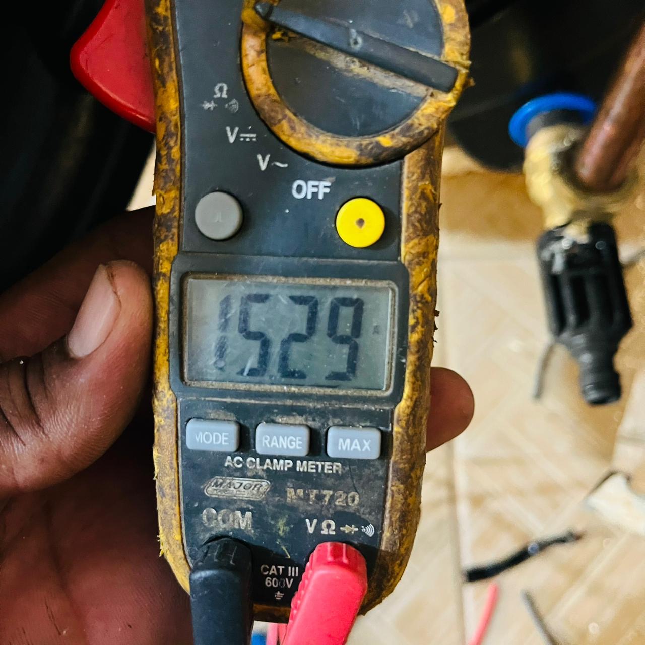 Electrician using an AC clamp meter to test circuit load during a Happ's Electrical fault-finding call-out
